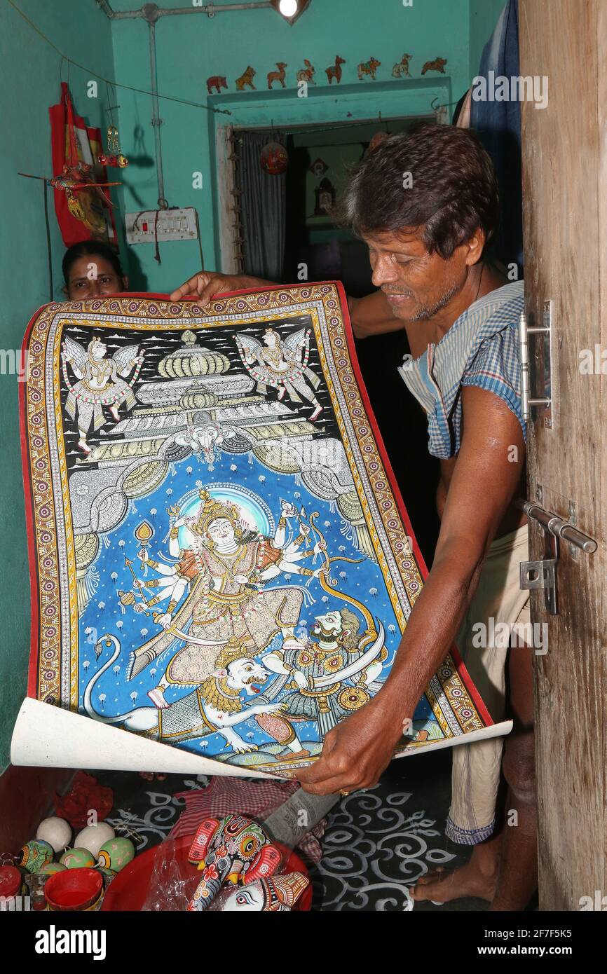 Un artigiano tribale che mostra Patachitra o Pattacitra un dipinto a spirale a base di stoffa Su tela per la vendita in un negozio di Raghurajpur villaggio Di Odisha Foto Stock