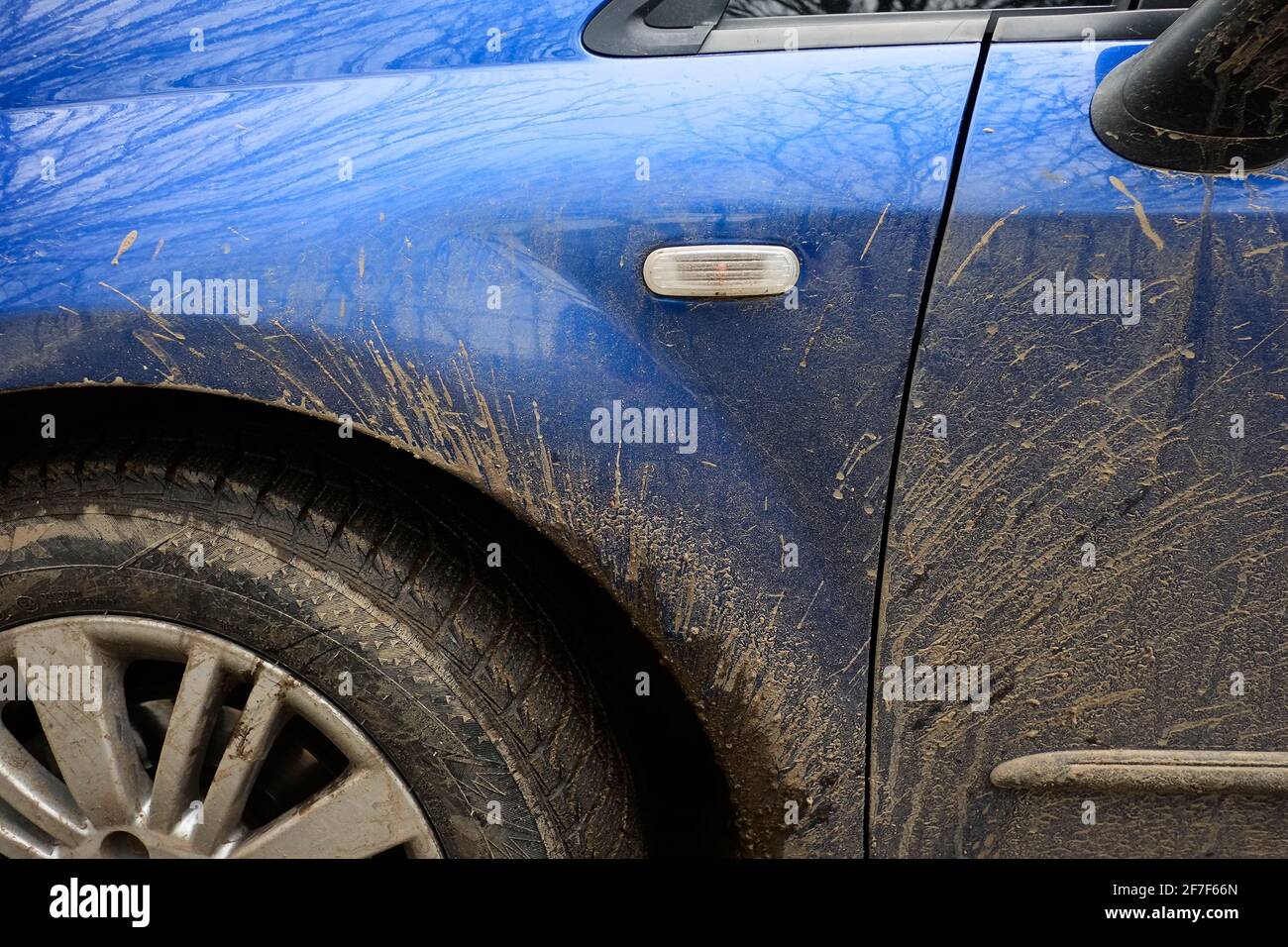 Schizzi di fango sul lato della vettura blu. Veicolo sporco in caso di pioggia su strada. Foto Stock