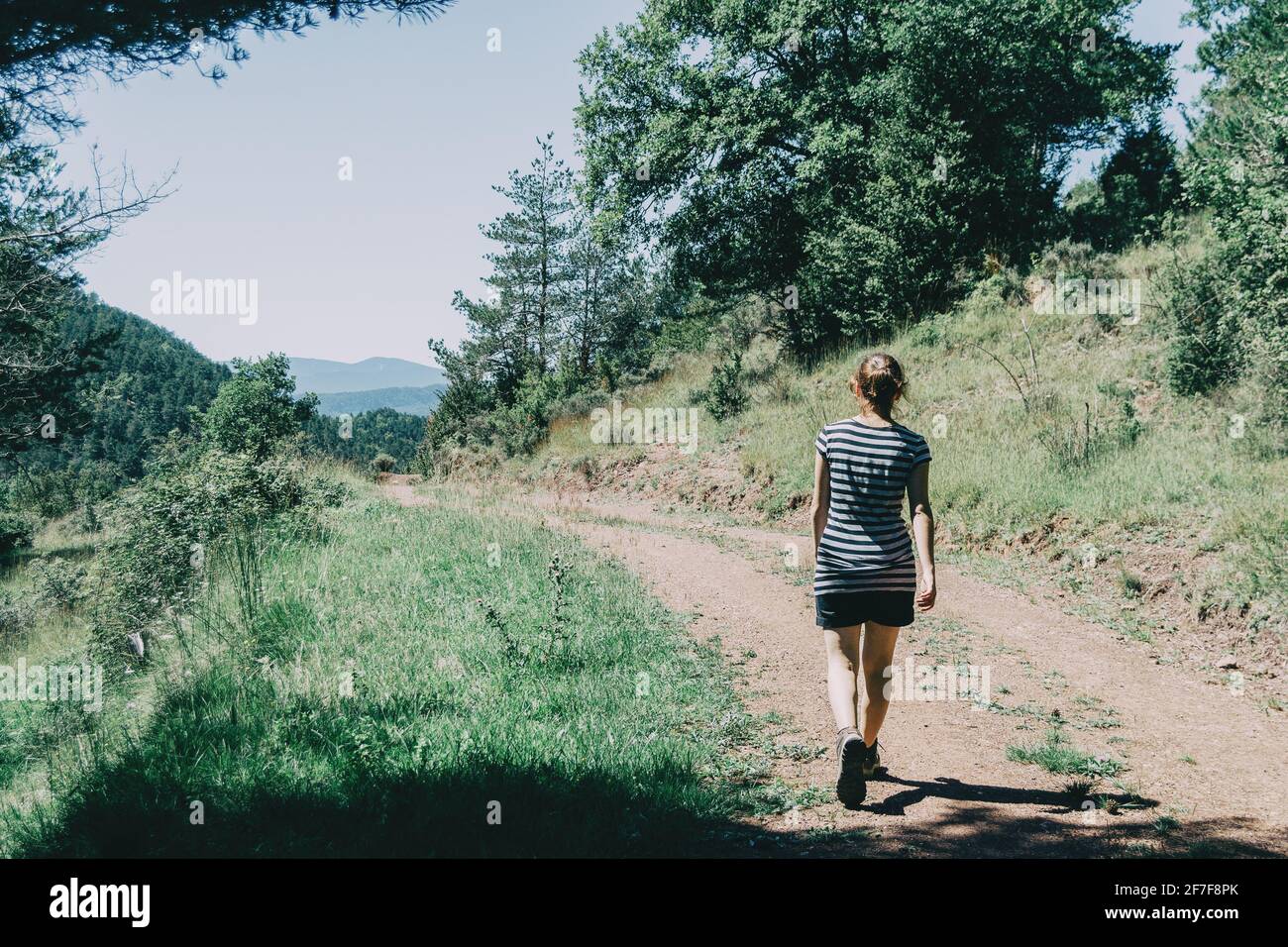 Ragazza che cammina lungo un piccolo sentiero nella montagna di Spagna. In una soleggiata giornata estiva Foto Stock