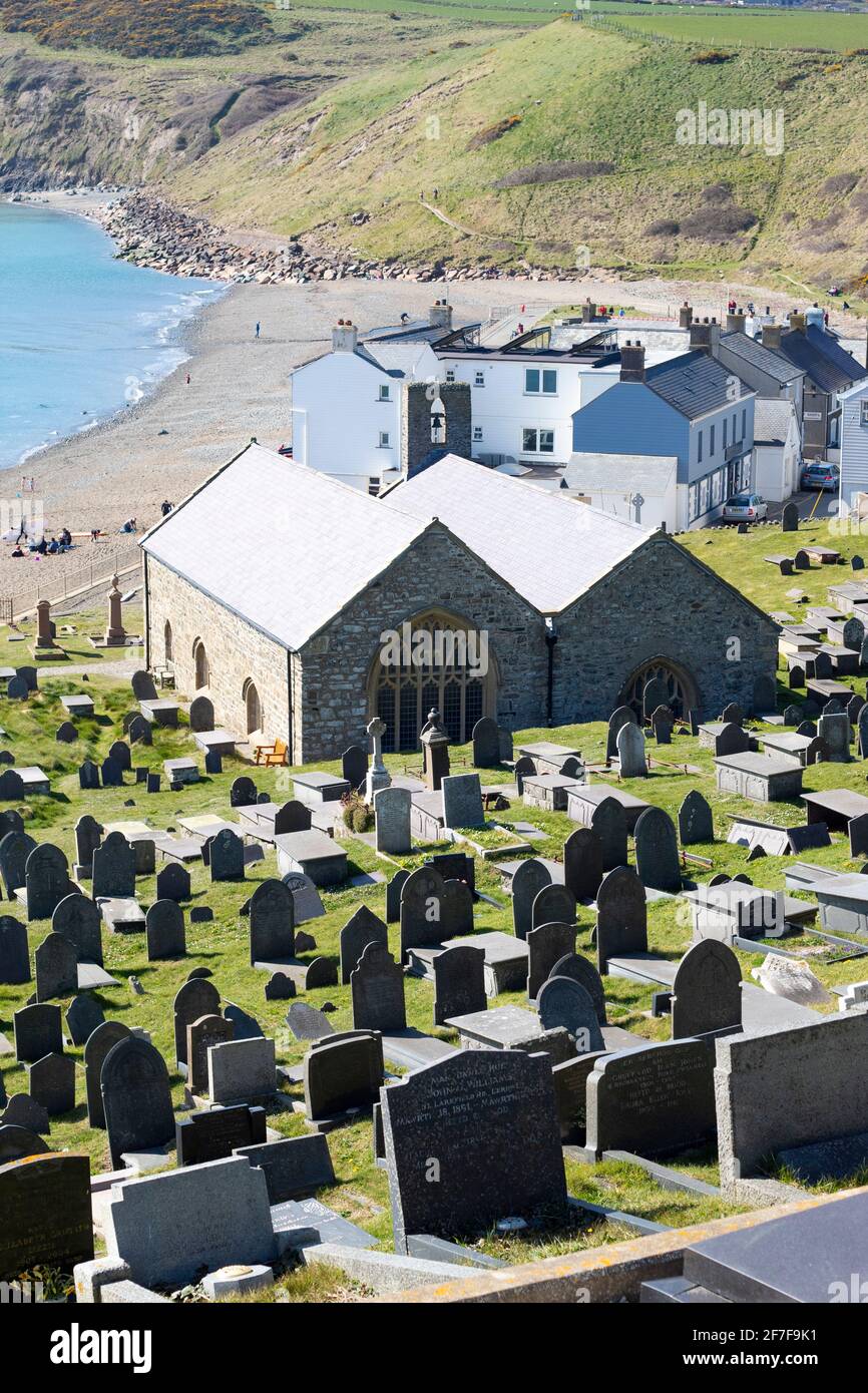 Aberdaron villaggio, Galles. Storica chiesa pellegrina di Saint Hywyns. L'angolo alto ha girato con la baia bella e la spiaggia come sfondo. Vista verticale. Foto Stock