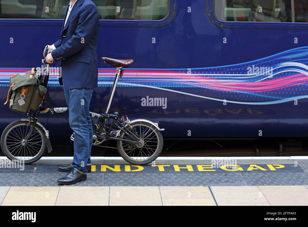 Commuter ad una stazione ferroviaria con la sua bici pieghevole Brompton che viaggia a lavoro, Londra, Regno Unito Foto Stock