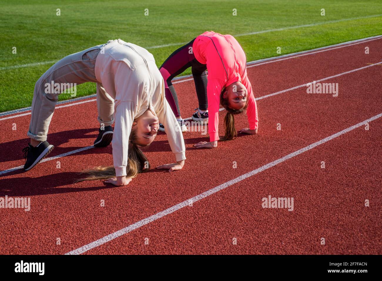 I ginnasti flessibili per ragazze si trovano in posizione granata sulla pista da atletica, flessibilità Foto Stock