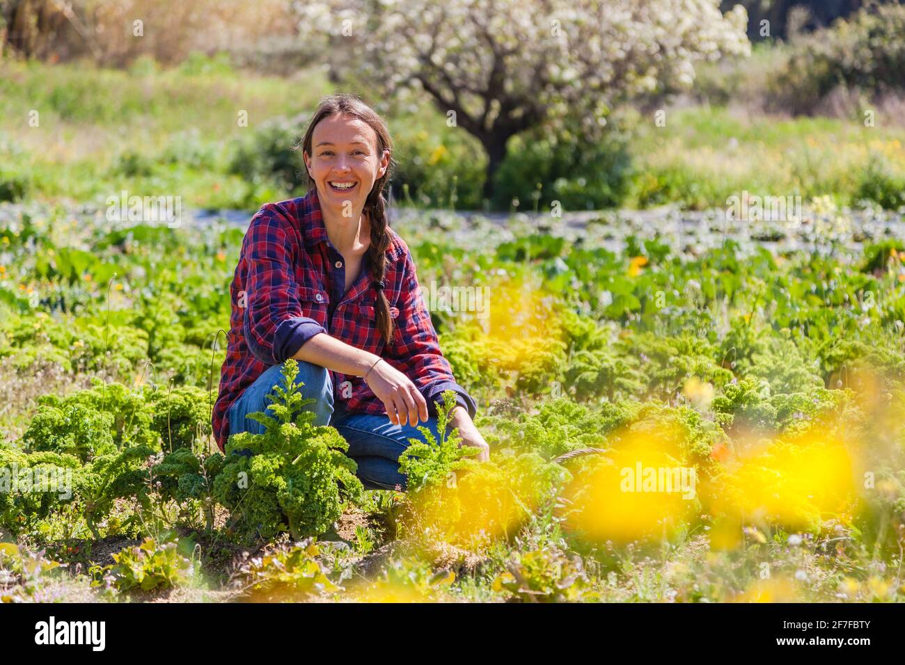 Ritratto candida di una donna naturale che lavora in un'azienda agricola biologica in un bellissimo paesaggio soleggiato; concetto di agricoltura sostenibile e stile di vita Foto Stock