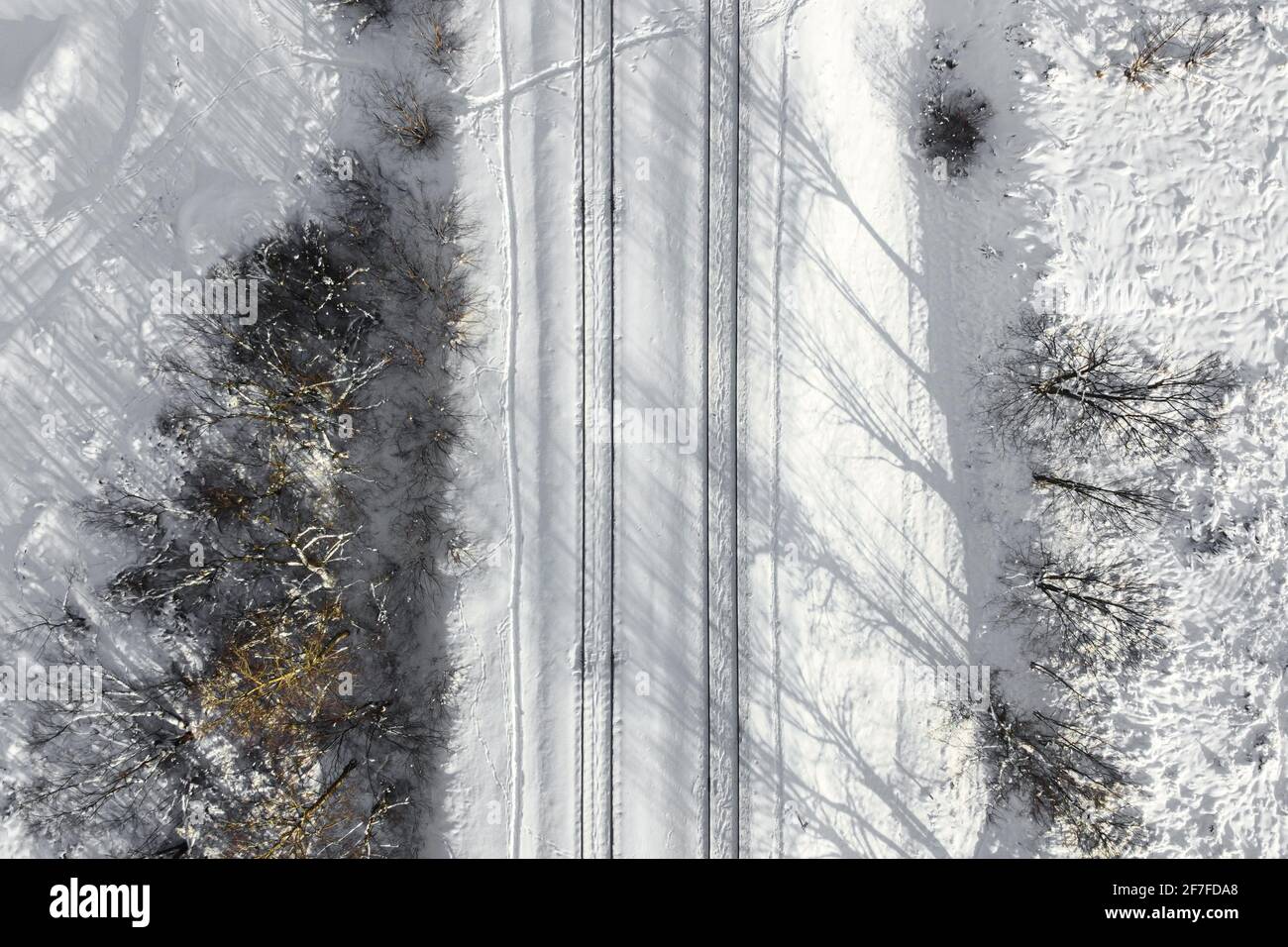Vista aerea di una ferrovia a doppio binario dopo una forte nevicata. Ferrovia invernale con neve bianca, vista dall'alto. Infrastrutture di trasporto, ferrovia, neve l Foto Stock