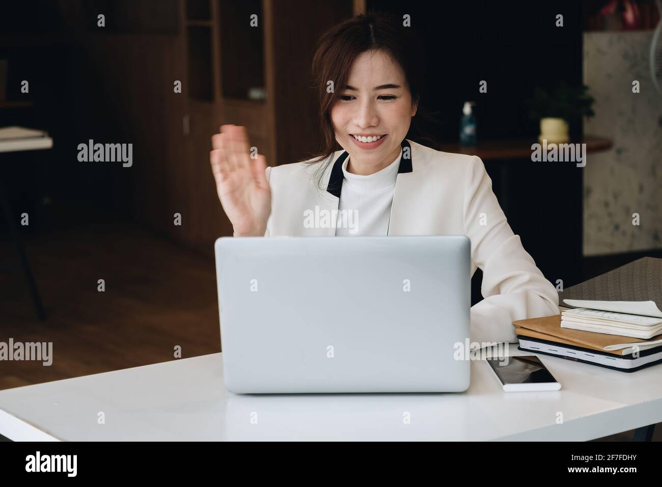 Concetto di videochiamata, giovane donna d'affari che utilizza un computer portatile per la connessione video con la famiglia, riunione remota, ad esempio Ciao, guardando la webcam. Foto Stock