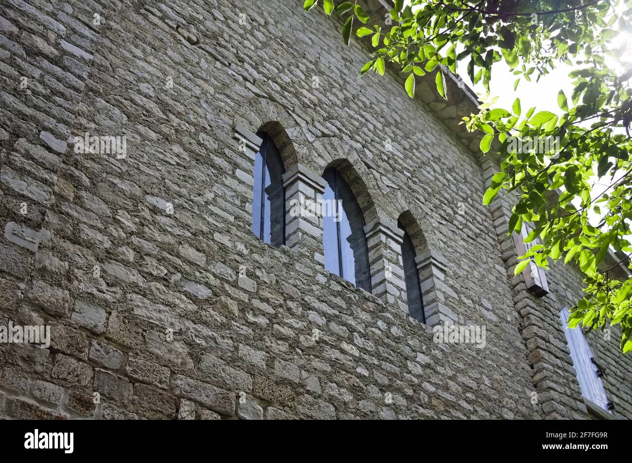 Tre vetrate gotiche in un'abbazia medievale con luce solare che filtra attraverso gli alberi (Marche, Italia, Europa) Foto Stock