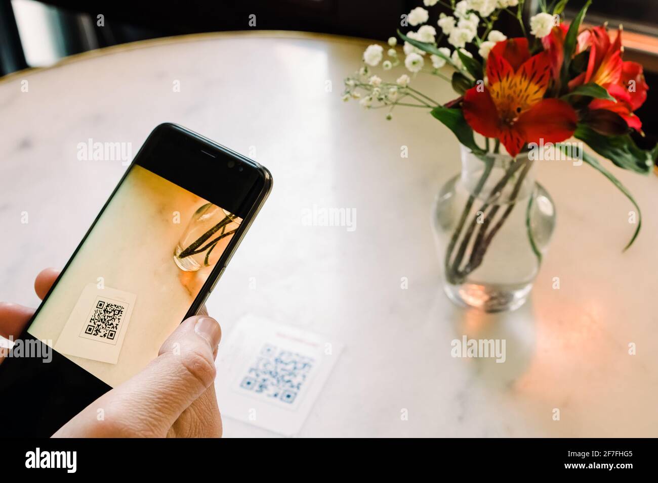 Uomo che scansiona il codice QR con il cellulare al ristorante. Foto Stock