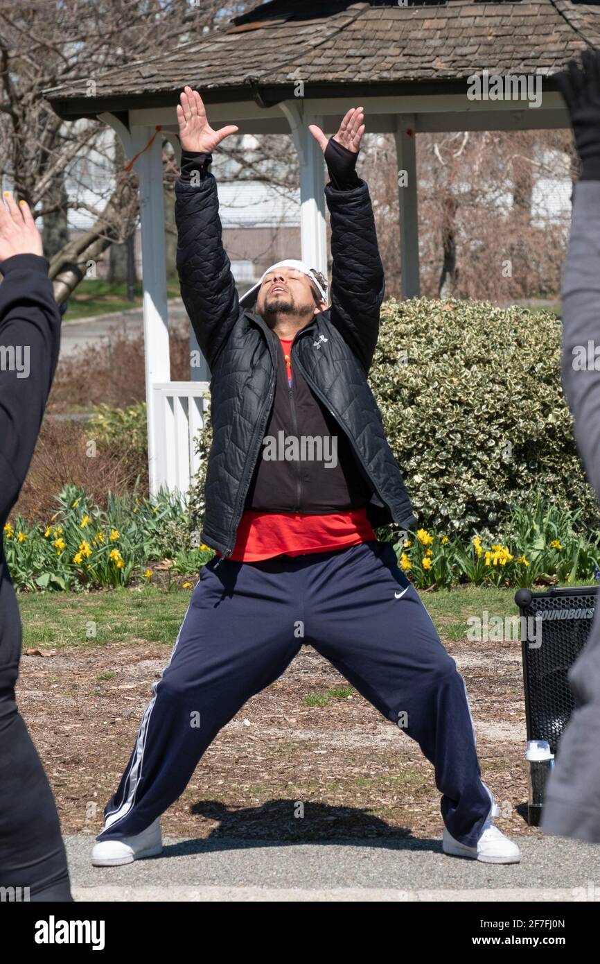 Un uomo conduce una lezione di Zumba attraverso un vigoroso allenamento di danza in un parco a Queens, New York City. Foto Stock