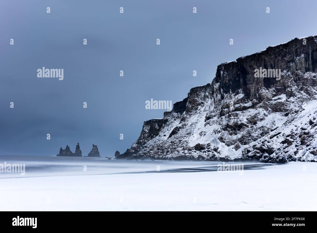 Black basalto mare stack e neve coperto spiaggia di sabbia nera, Vik, Islanda, regioni polari Foto Stock