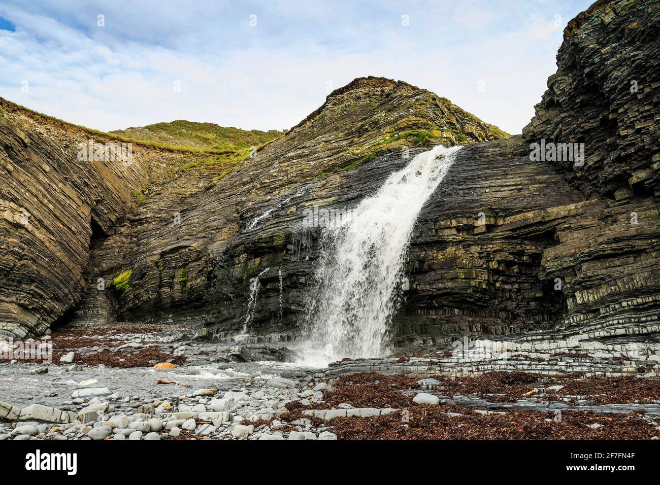 Insolita cascata sulla spiaggia, dove l'Afon Drywi si riverserà sulle acque della Siluria fino a Little Quay Bay, New Quay, Ceredigion, Galles, Regno Unito, Europa Foto Stock