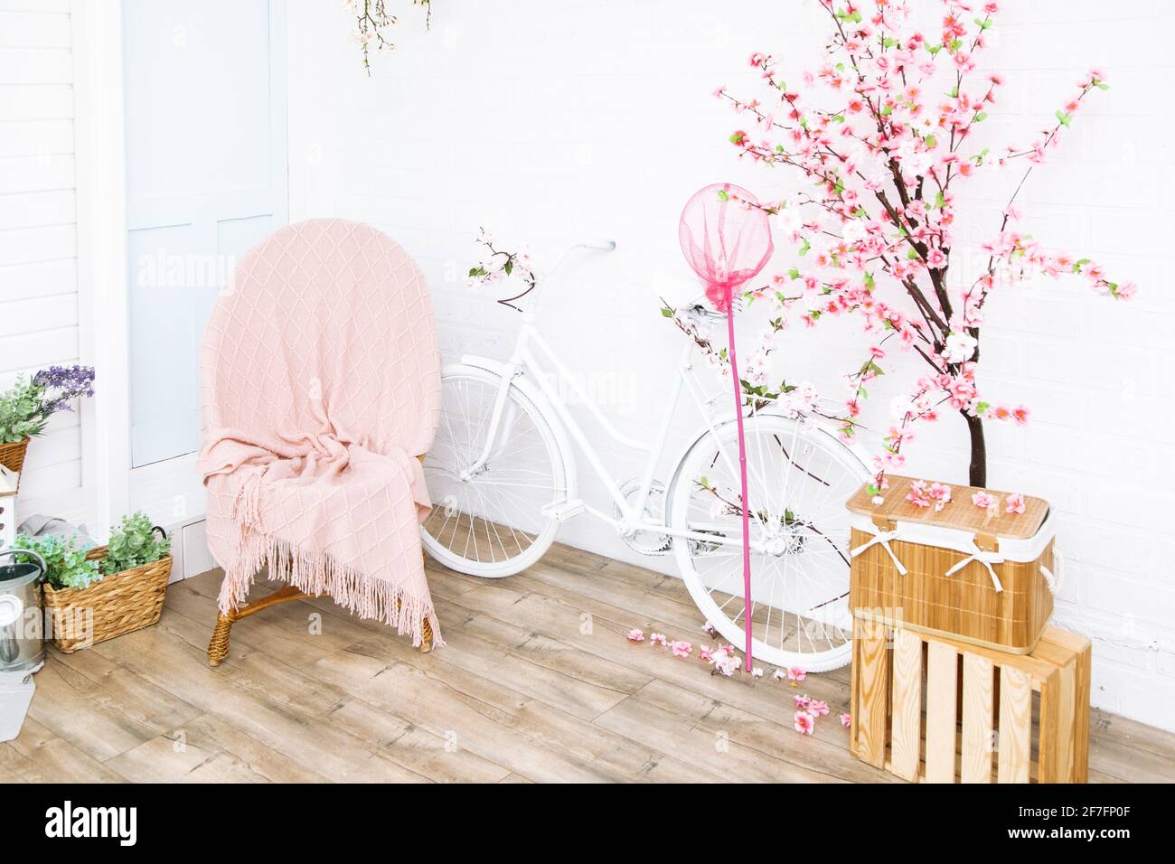 Retro bicicletta e poltrona in vimini sotto coperta con fiori sullo sfondo di casa bianca girato dal fronte al cortile posteriore. Decorazioni nel giardino in stile provenzale Foto Stock