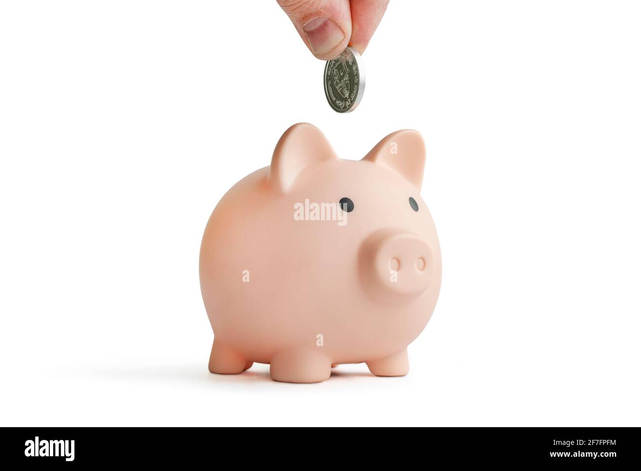 Banco di piggy per la moneta isolato su sfondo bianco. Mano con moneta su una banca piggy su sfondo bianco. Foto Stock