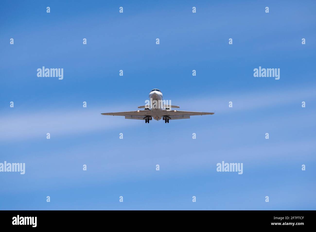 Business jet atterrando contro il cielo blu Foto Stock