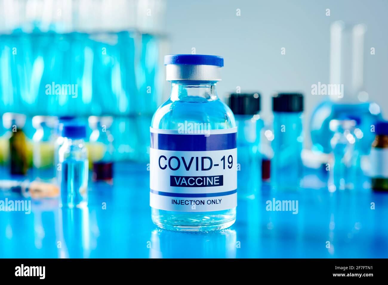 una fiala simulata del vaccino covid-19 su una tavola blu, in laboratorio Foto Stock