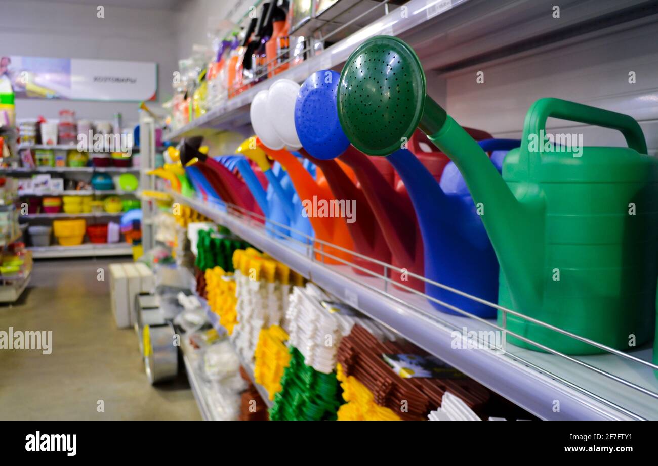 Primo piano di lattine di plastica multicolore che innaffiano sugli scaffali di un negozio con articoli per il giardinaggio. Foto Stock