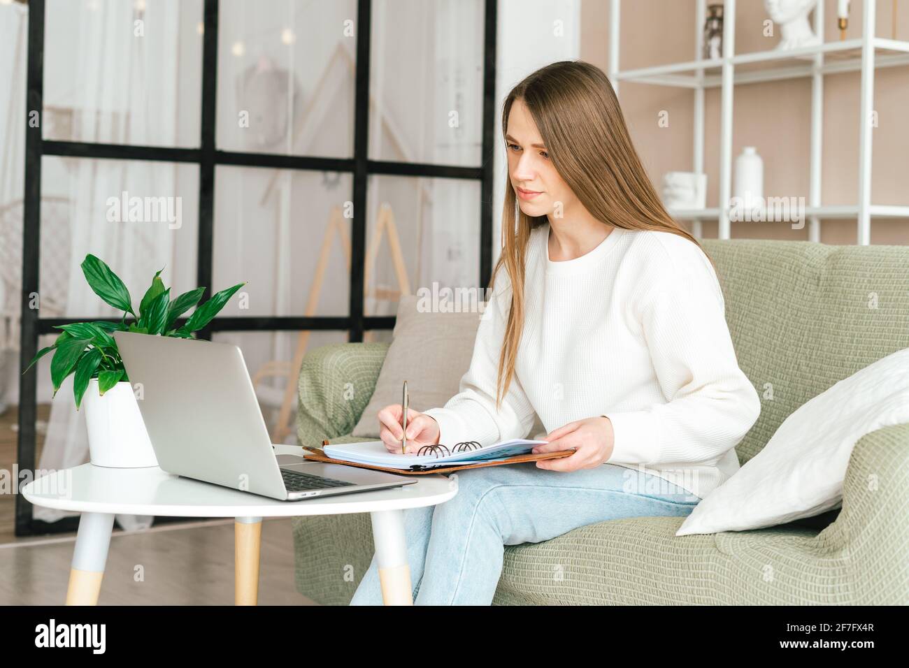 Donna scrive in notebook con notebook Foto Stock