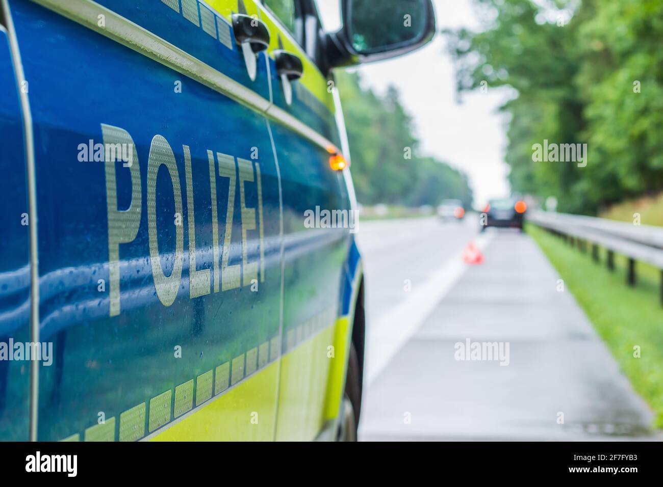 Auto di polizia in autostrada in una prospettiva laterale durante un incidente. Scritta polizia sul corpo con braccio e sfondo giallo. Spalla dura, corsia Foto Stock