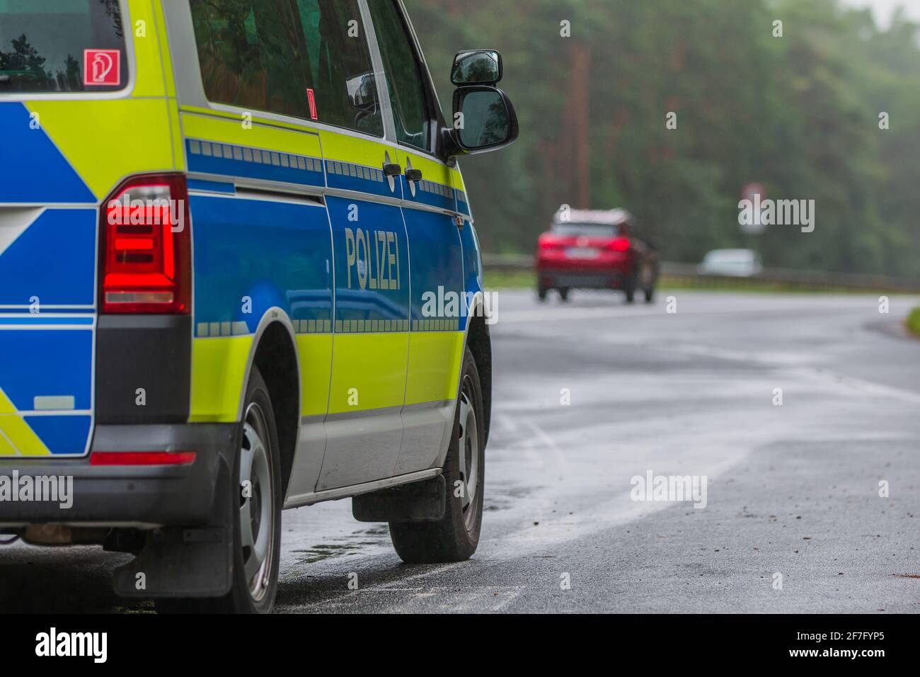 Vista laterale di un'auto di polizia in un arresto di emergenza vicino all'autostrada. Veicolo di polizia in vernice blu e gialla con strisce riflettenti. Lettera di polizia Foto Stock