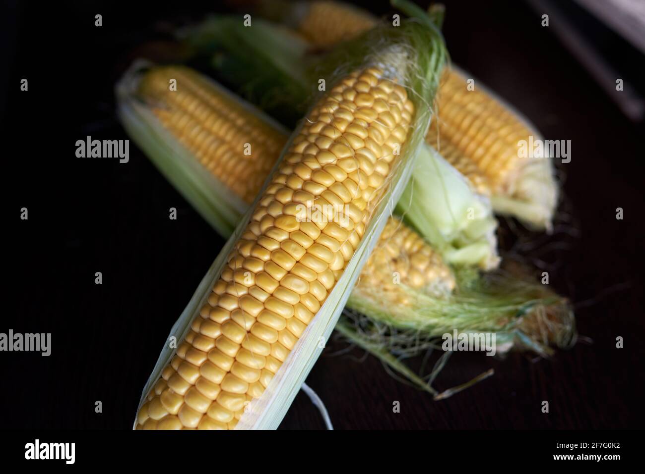 Quattro spighe dorate di mais con foglie. Tasto basso. Vista dall'alto Foto Stock