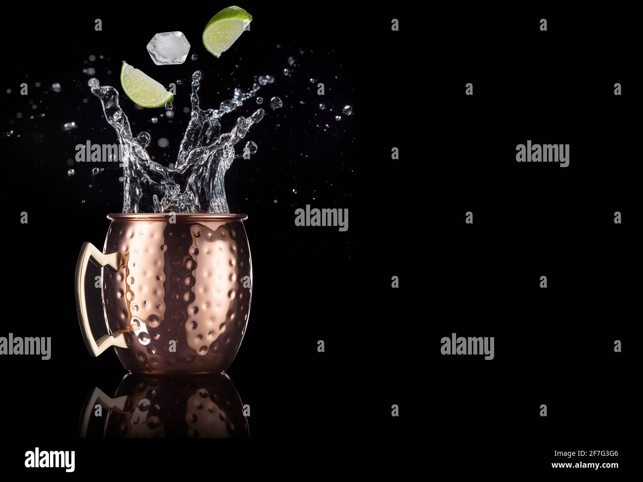 calce e ghiaccio cadono in un cocktail mule di mosca isolato su sfondo nero Foto Stock