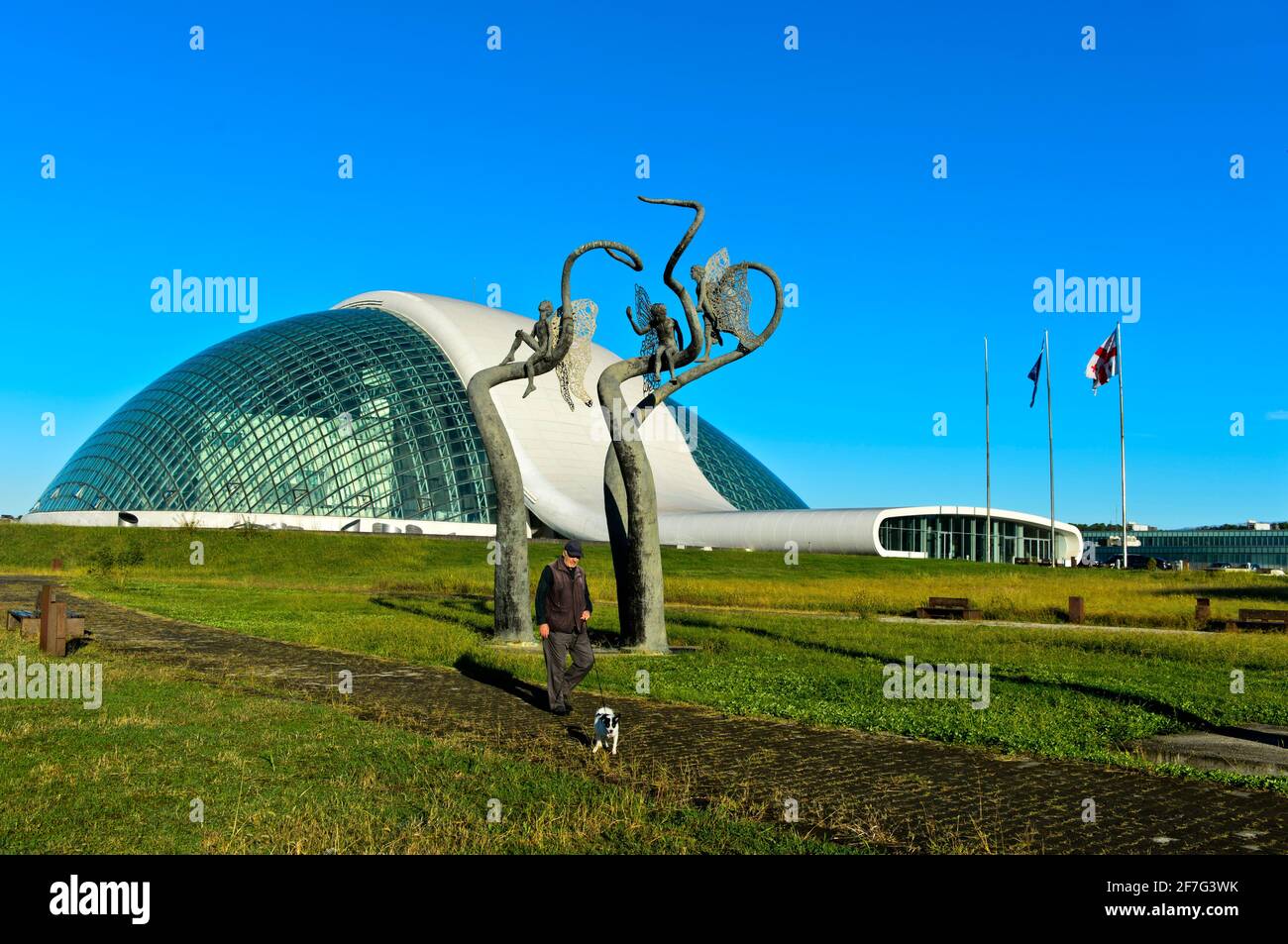 L'uomo conduce il suo cane fuori all'edificio del Parlamento georgiano in Kutaisi, architetti CMD Ingenieros, Kutaisi, Imereti, Georgia Foto Stock