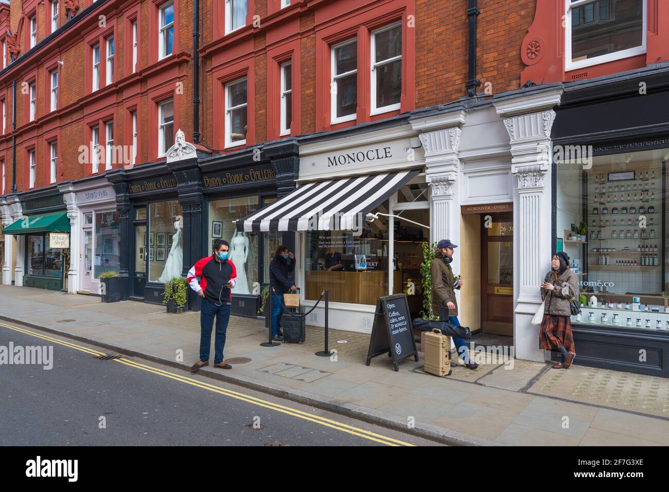 Il negozio di abiti da sposa della Rogue Gallery e il Monocle Cafe. Quattro persone si trovano in strada fuori dal caffè. Chiltern Street, Londra, Inghilterra, Regno Unito Foto Stock