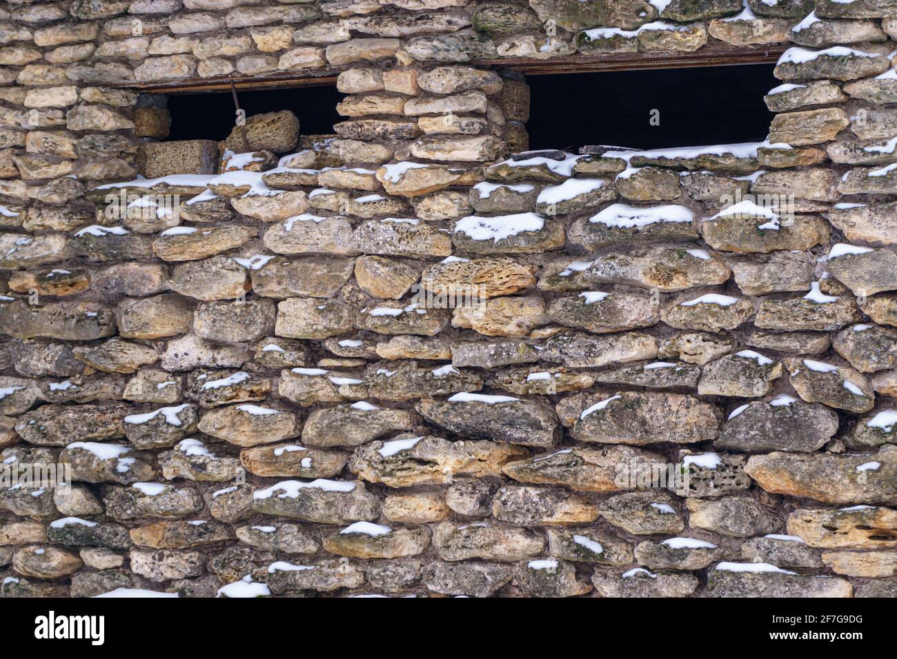 Un frammento di una parete con muratura e piccole finestre strette. La consistenza della pietra. Foto Stock