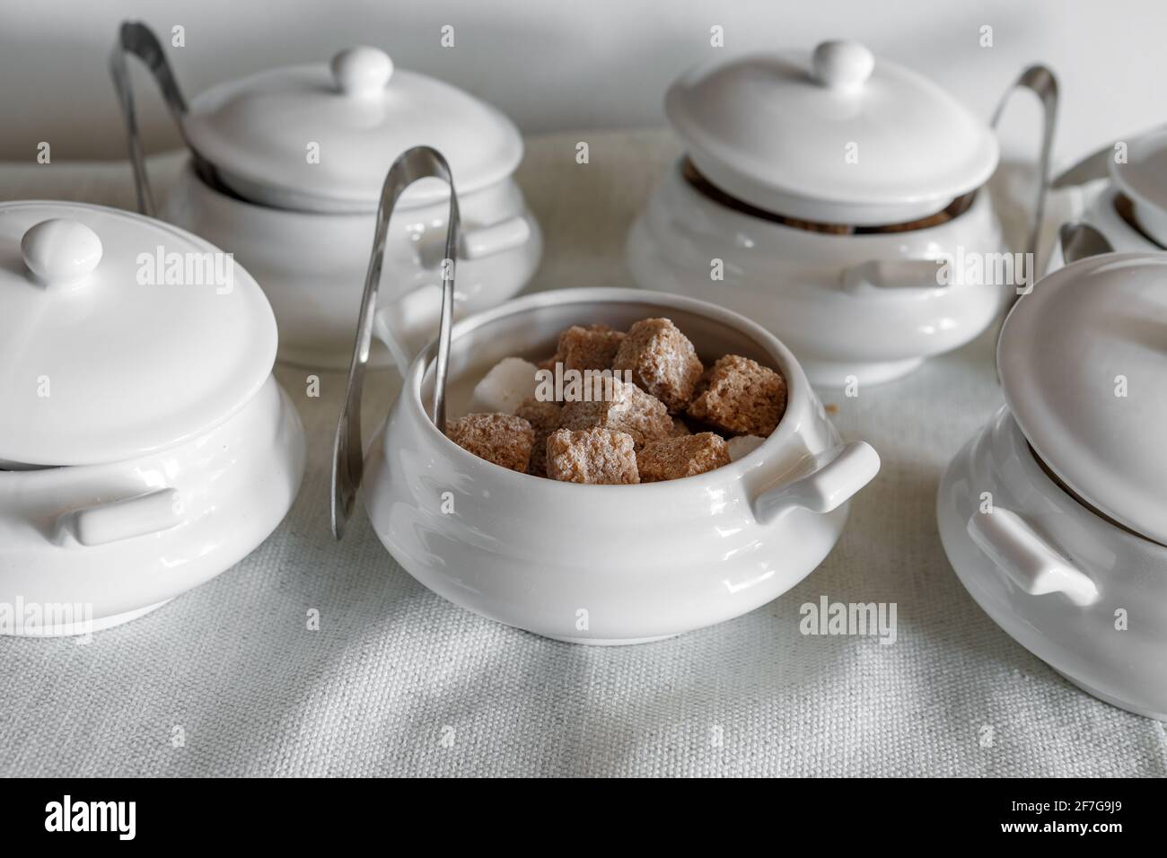 Le ciotole di zucchero con le pinze riempite di zucchero di frutta si trovano su un vassoio Foto Stock