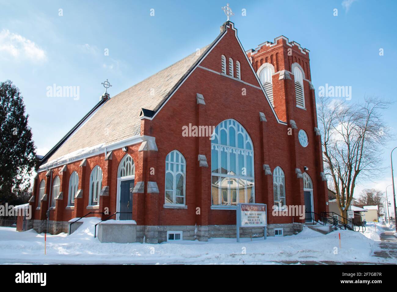 Lucan, Ontario, Canada - 6 febbraio 2021: Foto grandangolare della chiesa anglicana della Santa Trinità scattata in una mattinata di febbraio del cielo blu nel 2021. Le ciclicoli si appendono. Foto Stock