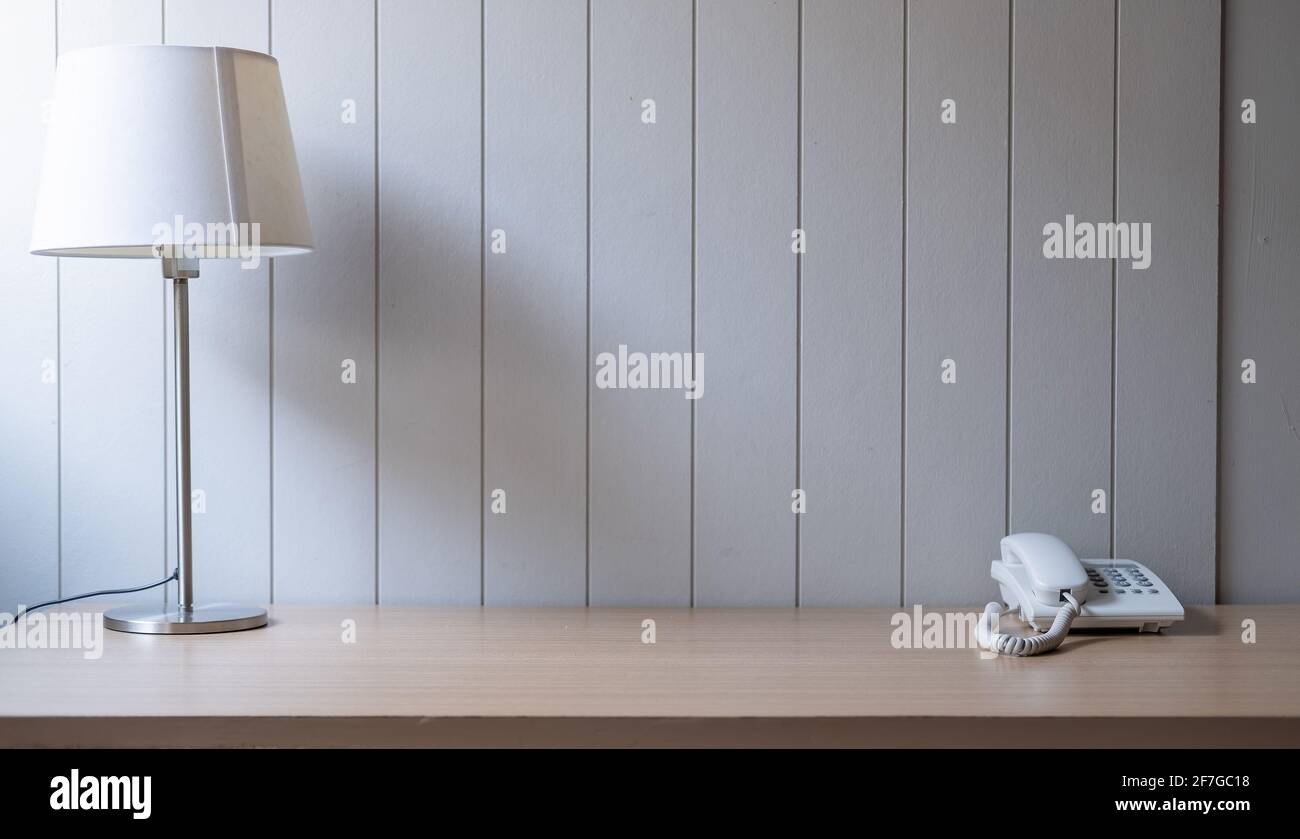 Posto di lavoro con spazio - lampada su vecchio tavolo in legno con spazio di parete in cemento grezzo in tonalità di bianco. Foto Stock