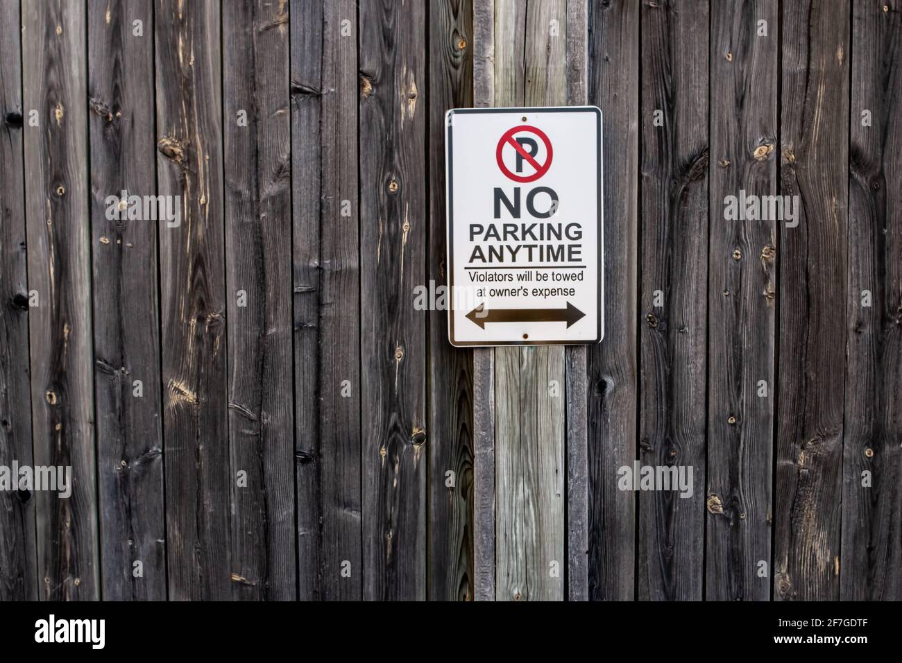 Un segno verticale e rettangolare di nessun parcheggio in qualsiasi momento è attaccato ad una recinzione di legno intemperie a Londra, Ontario, Canada, febbraio 2021. Foto Stock