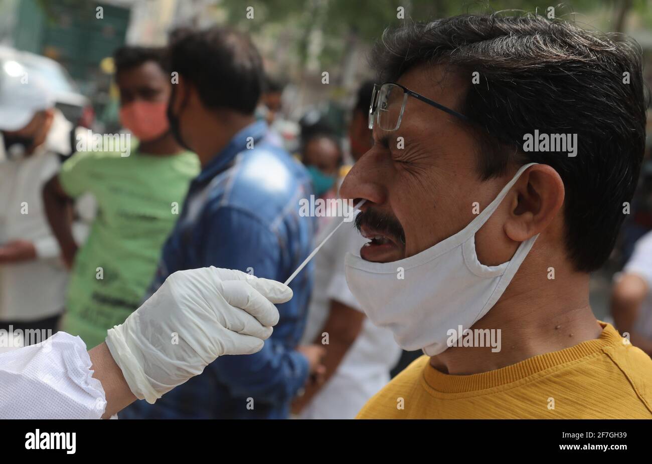 Un uomo che ottiene il suo campione raccolto da un operatore sanitario durante il prelievo di campioni di tampone per il test di reazione a catena della polimerasi a trascrizione inversa (RT-PCR) Covid-19 in tempo reale sul lato della strada a Nuova Delhi. Foto Stock