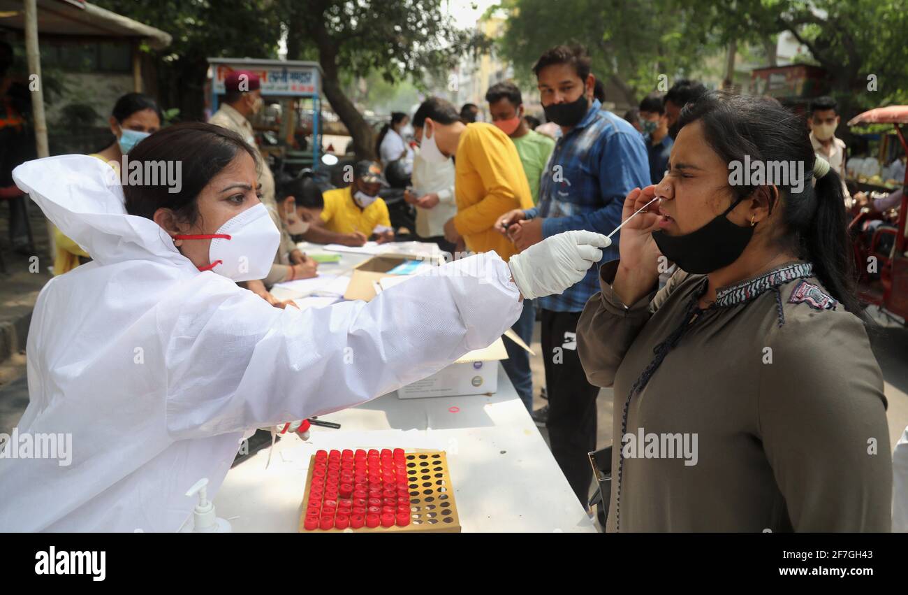 Una donna che riceve il suo campione raccolto da un operatore sanitario durante il prelievo di campioni di tampone per il test di reazione a catena della polimerasi a trascrizione inversa (RT-PCR) Covid-19 in tempo reale sul lato della strada a Nuova Delhi. Foto Stock