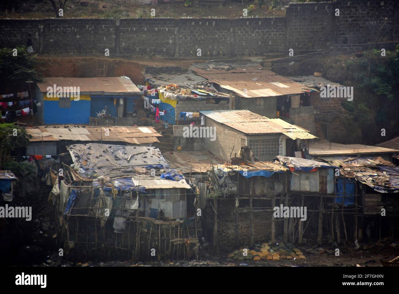 Vista dal terminal dei container sulla città di Shanty a Freetown in Sierra Leone. Case demolite e povere circondate da rifiuti e barche da pesca in legno. Foto Stock
