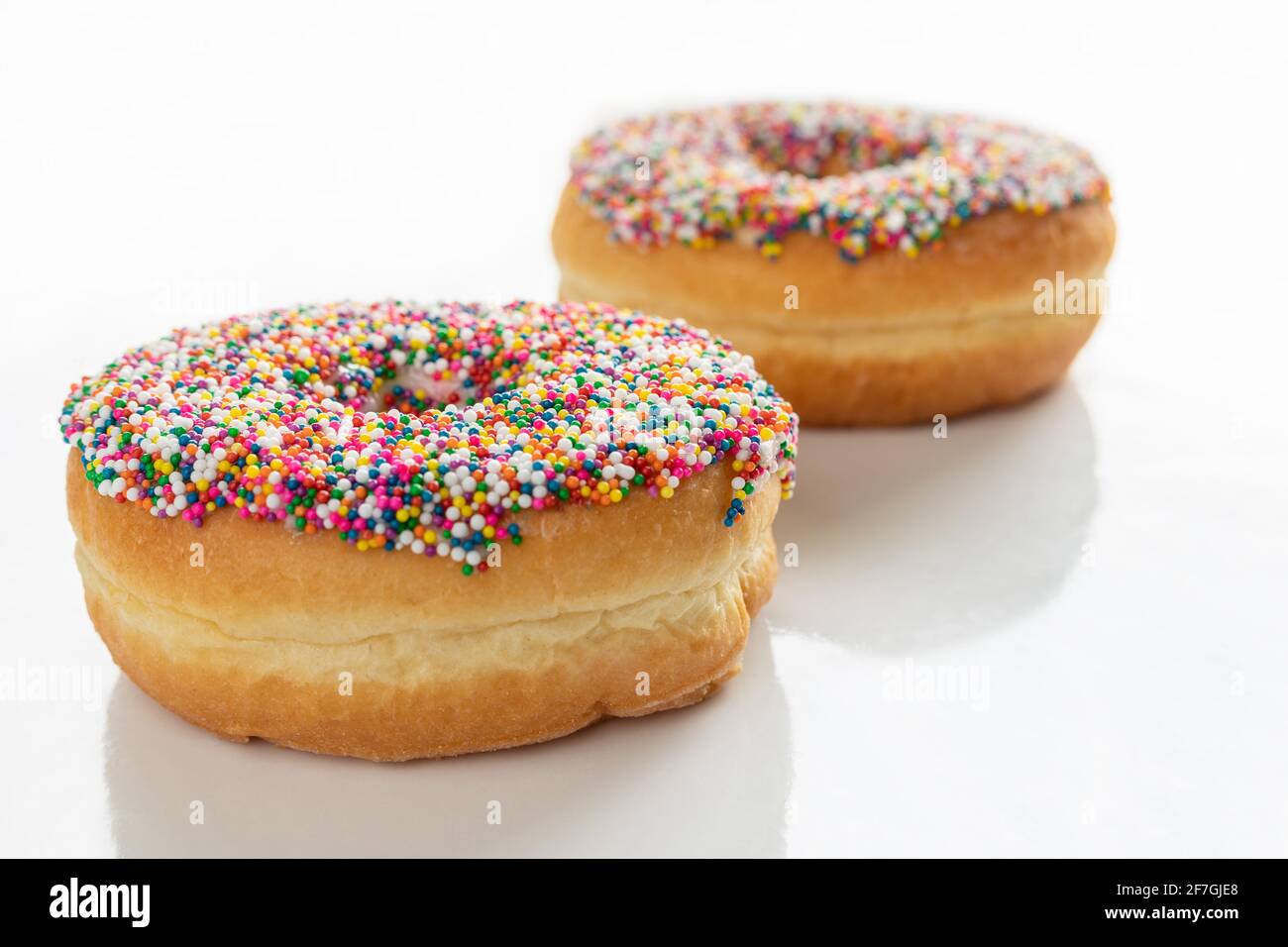 Ciambella con coloratissimi spruzzi su sfondo bianco. Visualizzazione ad angolo alto con spazio di copia per il testo. Foto Stock