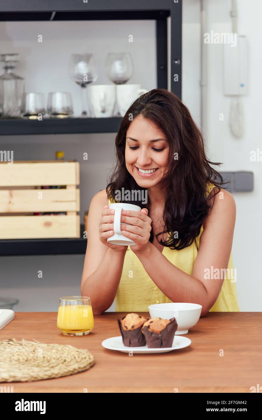 Giovane donna che ha fatto colazione in cucina a casa. Concetto di vita domestica. Foto Stock