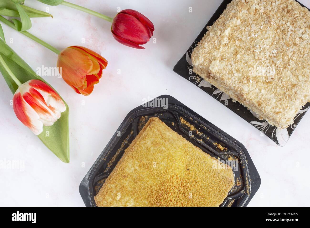 Tre tulipani rossi e una deliziosa torta sul tavolo delle feste. Foto Stock