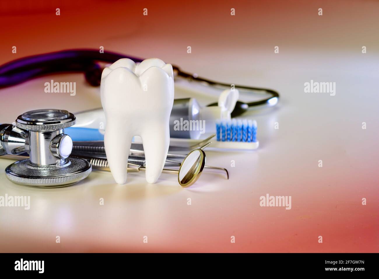 Dente bianco grande sano e diversi strumenti per la cura dentale. Su fondo dentale a gradiente con stetoscopio. Foto Stock