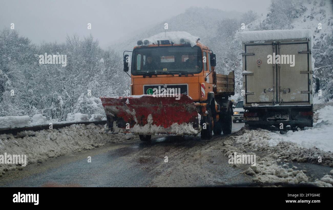 Un carro bulldozer sta eliminando la neve sulla strada distrutta Foto Stock