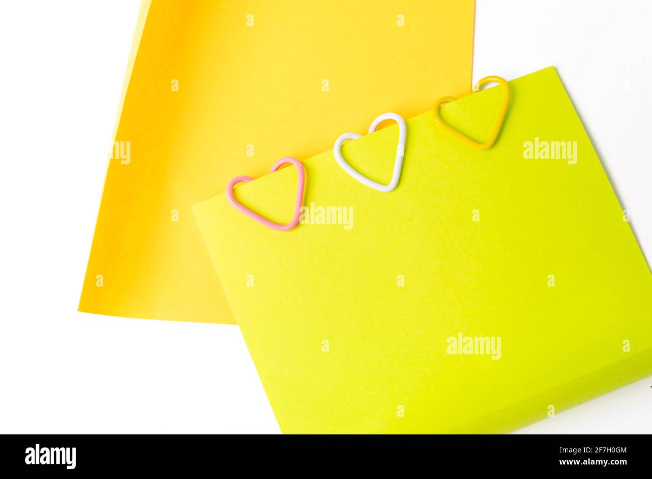 Graffette a forma di cuore su note adesive fluorescenti su sfondo bianco. Foto Stock