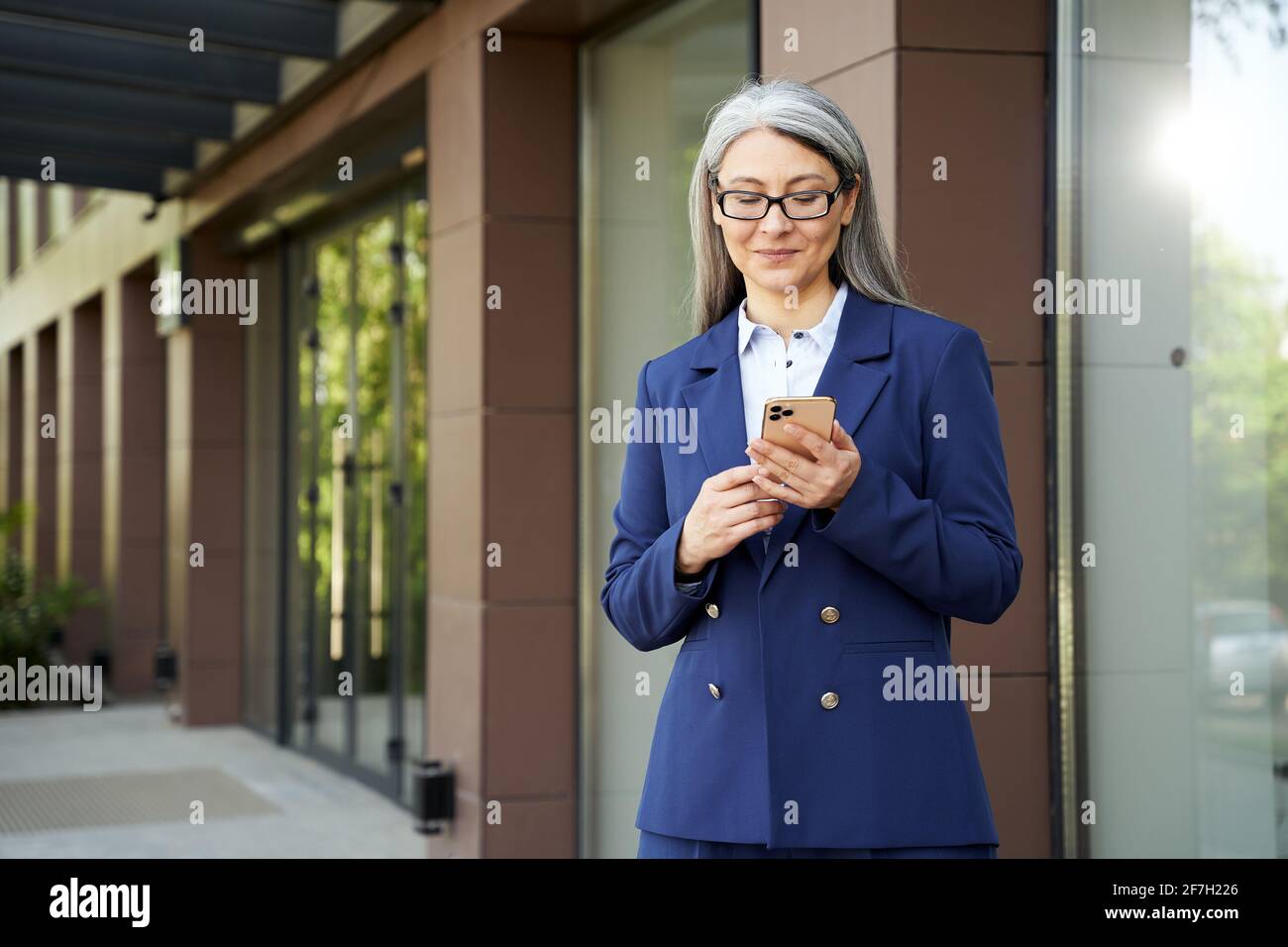 Tranquilla donna d'affari di mezza età che controlla il suo telefono Foto Stock