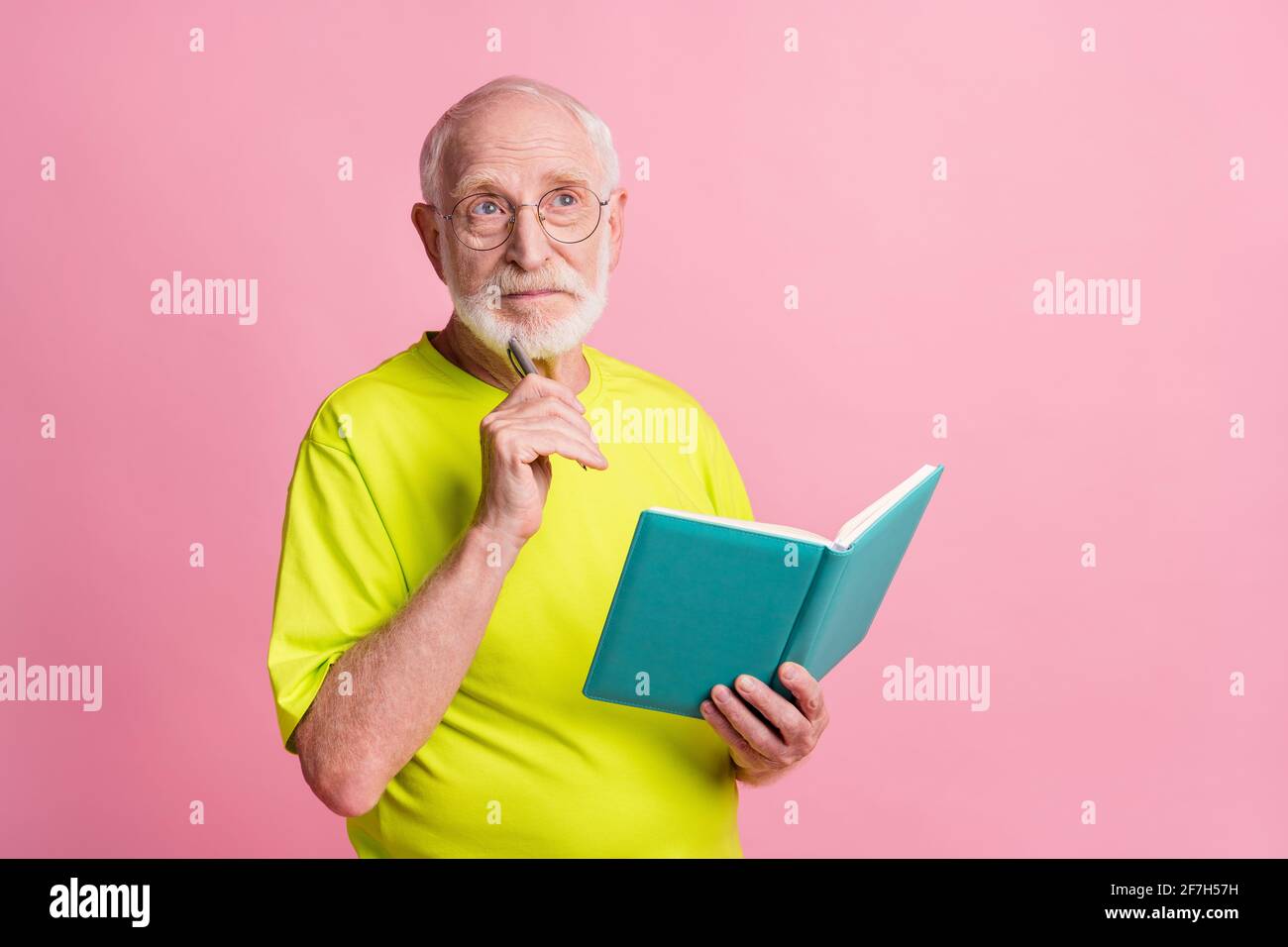 Ritratto di gravi pensionati scrivere copybook guardare spazio vuoto usura occhiali t-shirt di colore verde isolata su sfondo di colore rosa pastello Foto Stock