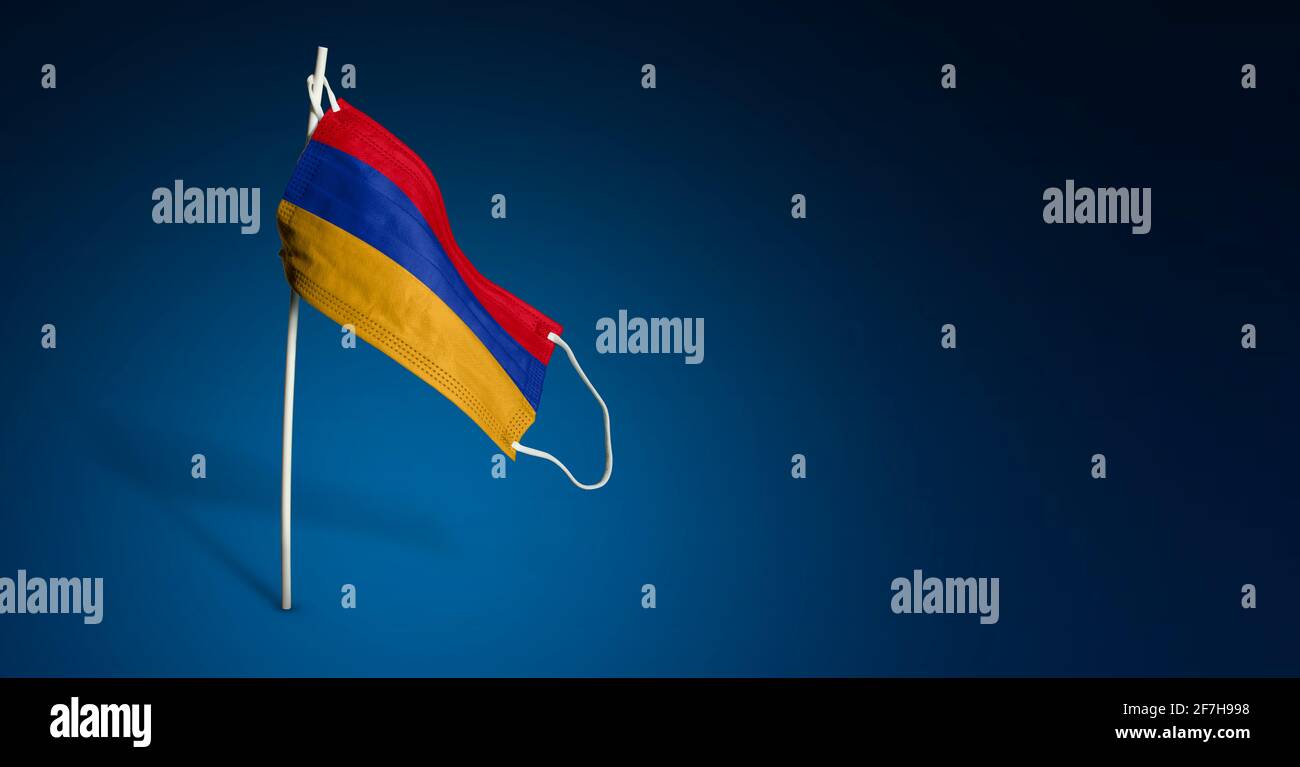 Maschera Armenia su sfondo blu scuro. Bandiera ondulata dell'Armenia dipinta su maschera medica sul palo. Flag di attacco del virus. Concetto del banner della Fight ag Foto Stock