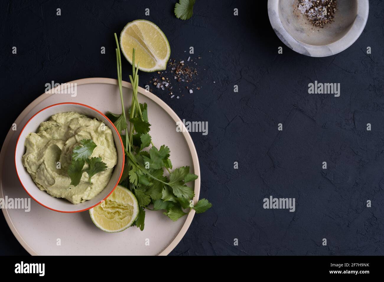 Hummus avocado tuffo su tavolo grigio scuro, vista dall'alto, tradizionale antipasto messicano in ciotola di ceramica Foto Stock
