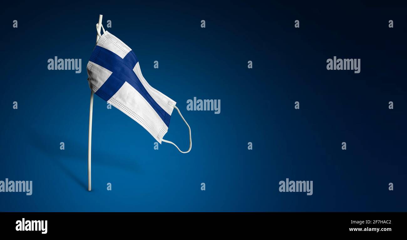 Maschera finlandese su sfondo blu scuro. Bandiera ondulata della Finlandia dipinta su maschera medica sul palo. Flag di attacco del virus. Concetto del banner della Fight ag Foto Stock