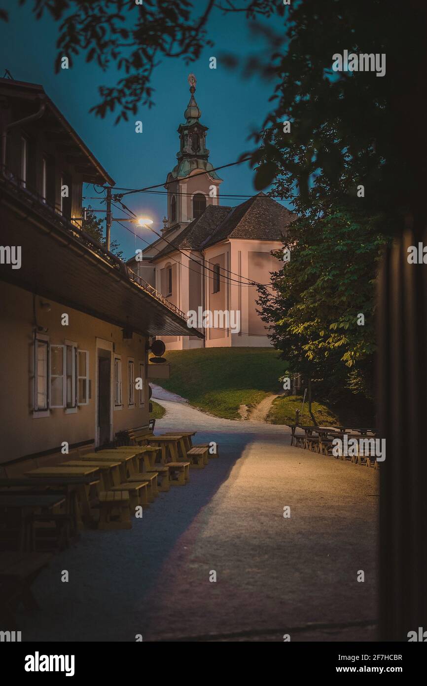 Spaventosa foto notturna di una chiesa e di una casa sulla collina di Roznik a Lubiana. Ambiente oscuro e torbido vicino a una chiesa. Ottimo per halloween spooky backgr Foto Stock