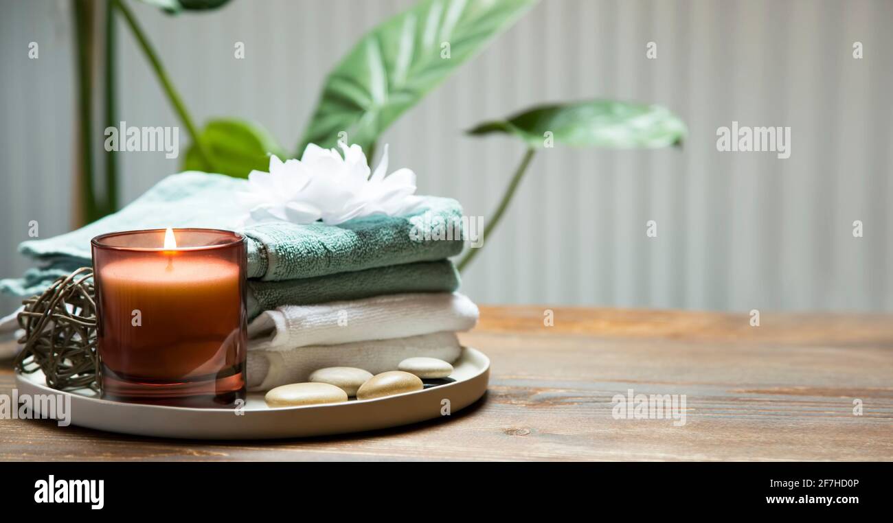 Ambiente termale con candela, asciugamani e pietre da massaggio, centro benessere e composizione wellness Foto Stock