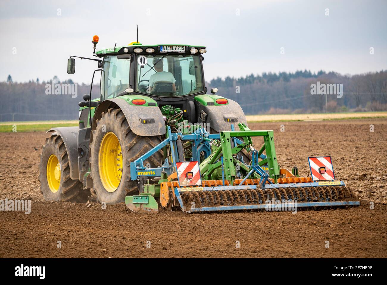 Trattore con un erpice di potenza che prepara il suolo di un campo per piantare, agricoltura, molla, Foto Stock