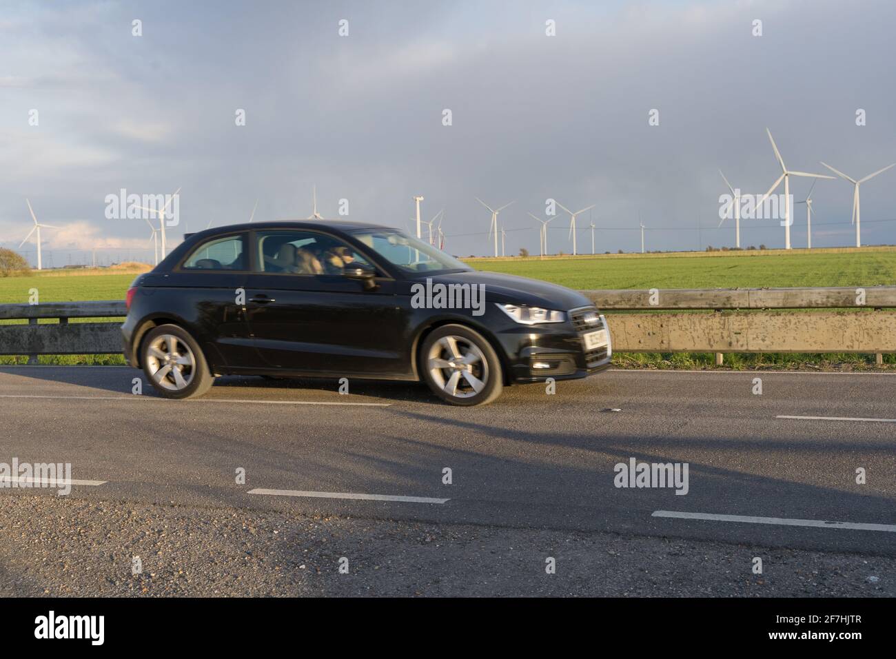 Auto su strada vicino al parco eolico Little Cheyne Court con più turbine nella costa meridionale, Sussex orientale, Inghilterra Foto Stock