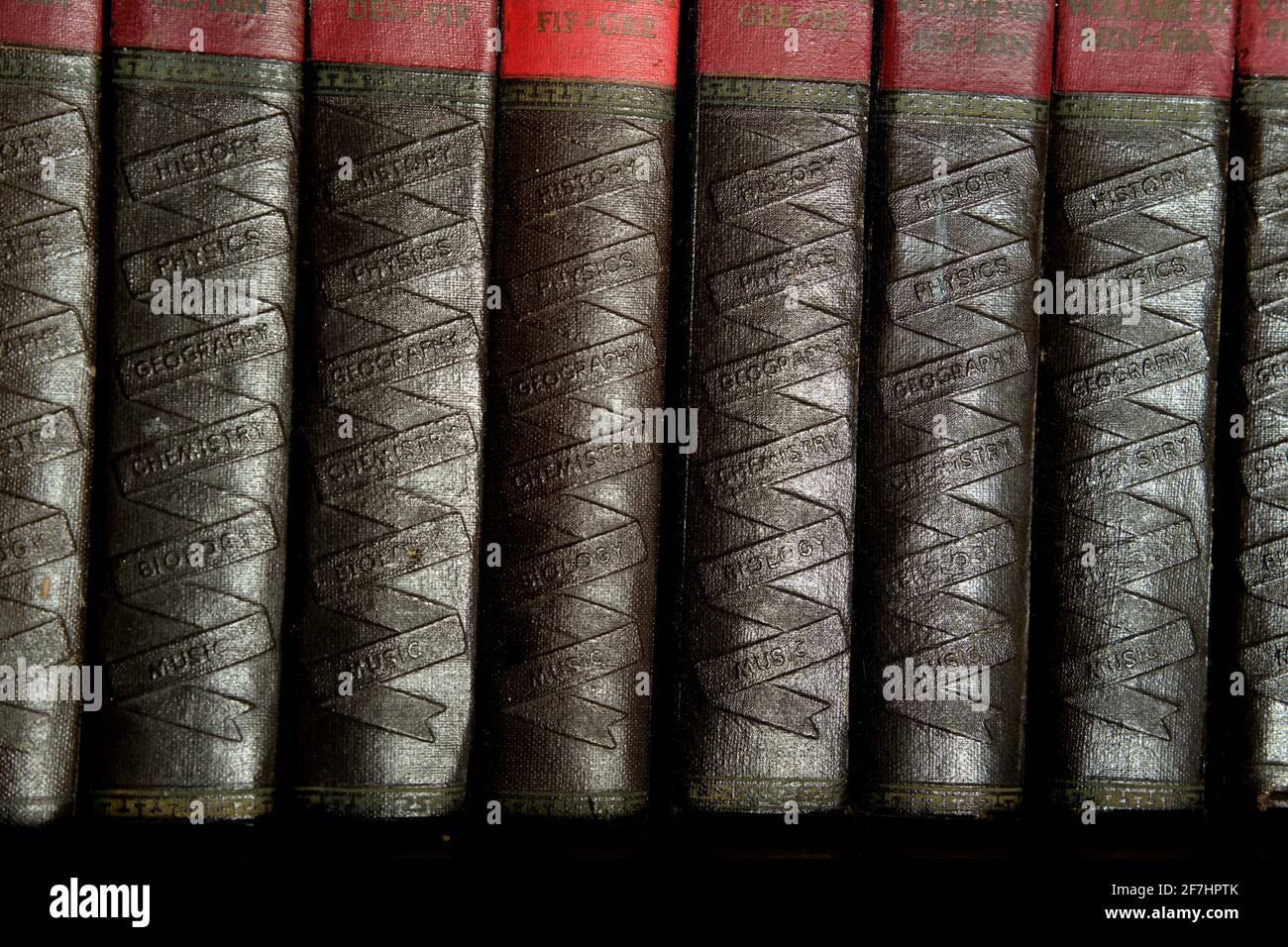 Una collezione di libri antichi rossi e neri. Le spine con strumenti chiamano le scienze in un modello a nastro. Foto Stock